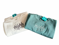 Two folded sweatshirts, one beige and one green, with 'tired mom's club' text on a white background..