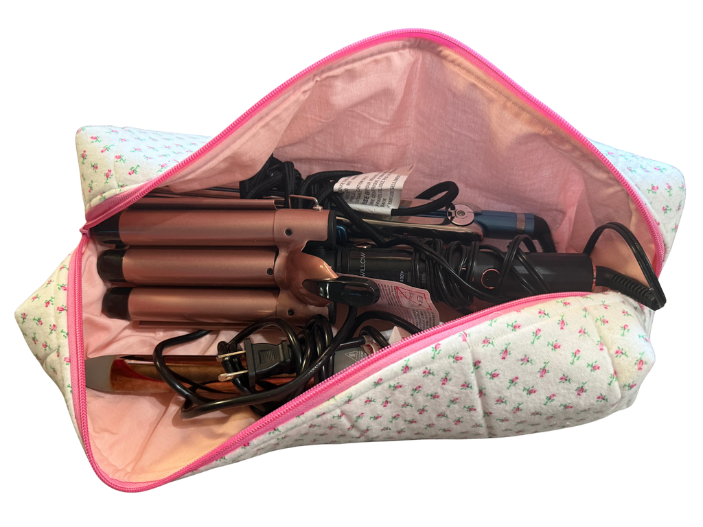 Set of hair straighteners and curlers in a floral-patterned pouch on a white background