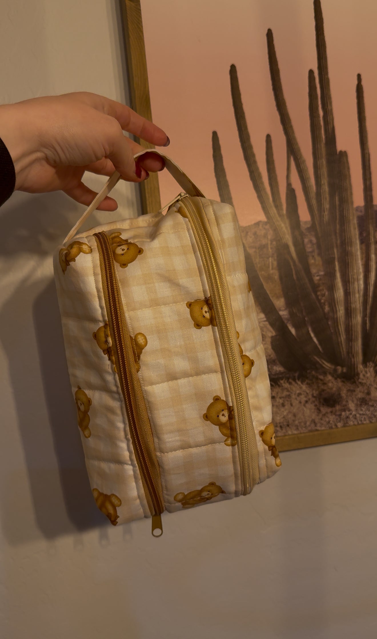 Small quilted handbag with gold accents held by a hand against a neutral background