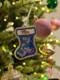 Decorative stocking ornament with 'Mia' on a Christmas tree with colorful ornaments and lights.