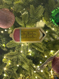Decorative sign ornament on a Christmas tree with blurred lights in the background